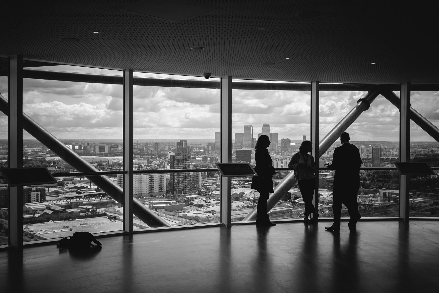 Executivos conversando diante da vidraça de um edifício, com a cidade ao fundo